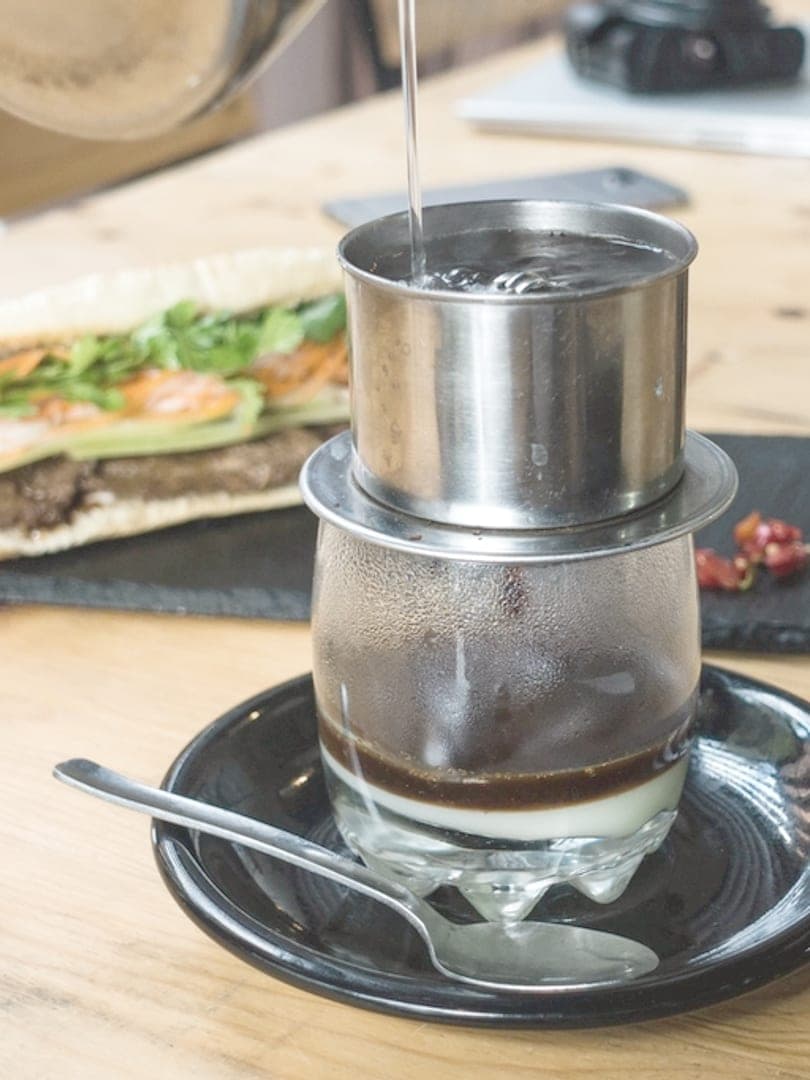 Phin cà phê Việt Nam nhỏ giọt bên đĩa bánh mì